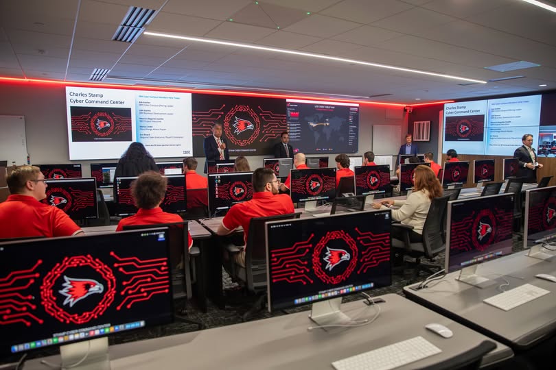 People sitting in classroom environment with multiple computer screens